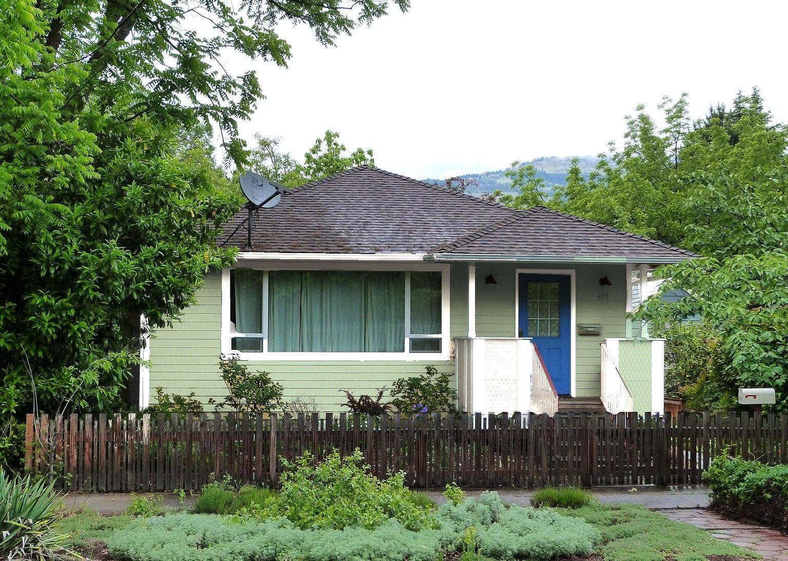 The same bungalow in a soft sage green with crisp white trim.